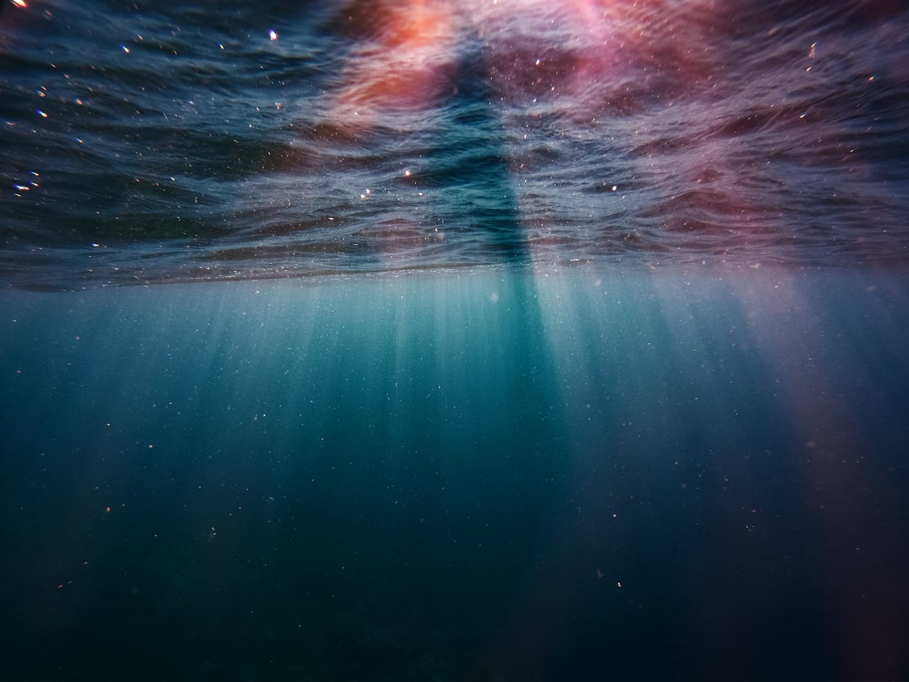 Captivating underwater view of sunlight rays penetrating the ocean surface, creating a serene seascape.