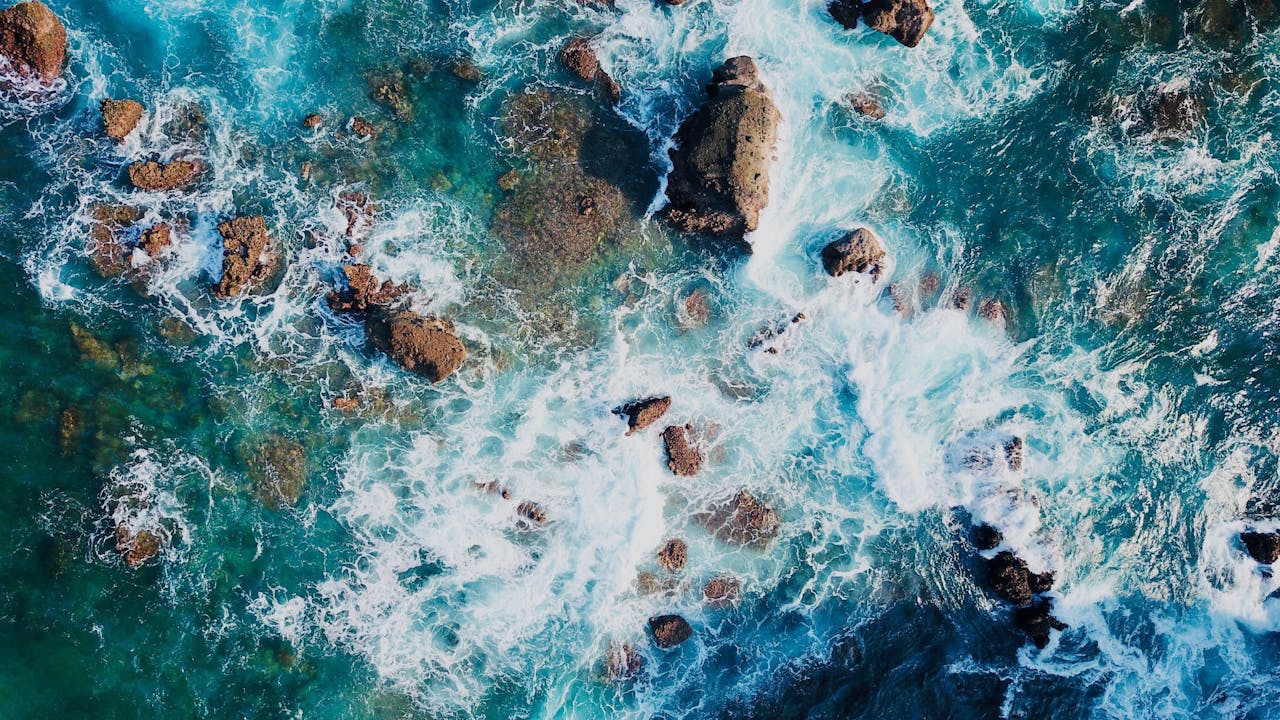 Stunning aerial view of ocean waves crashing against rocks, creating a beautiful natural pattern.
